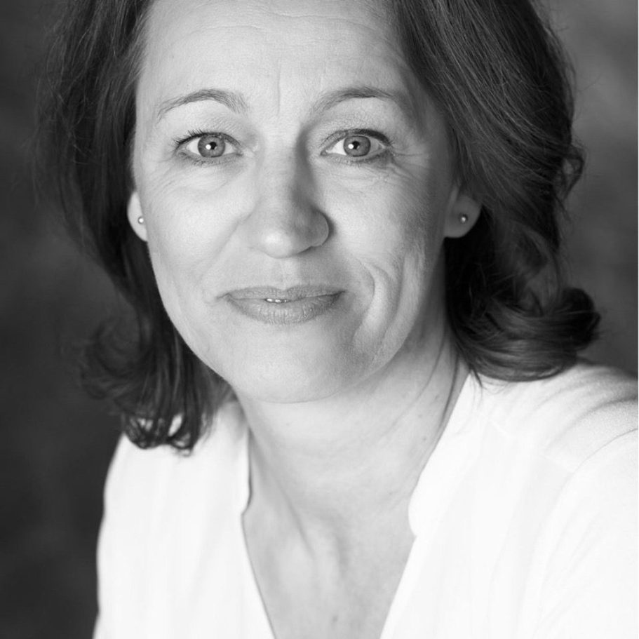 Porträt einer Frau mit schulterlangen, lockigen Haaren und freundlichem Gesichtsausdruck.